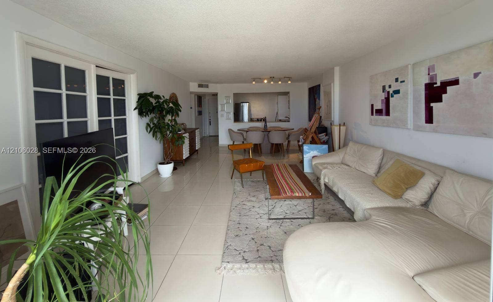 2780 NE 183rd Street, #1605, Aventura, FL 33160 Open-concept living space featuring large-format ceramic tile flooring, a pass-through opening, and glass-paneled double doors