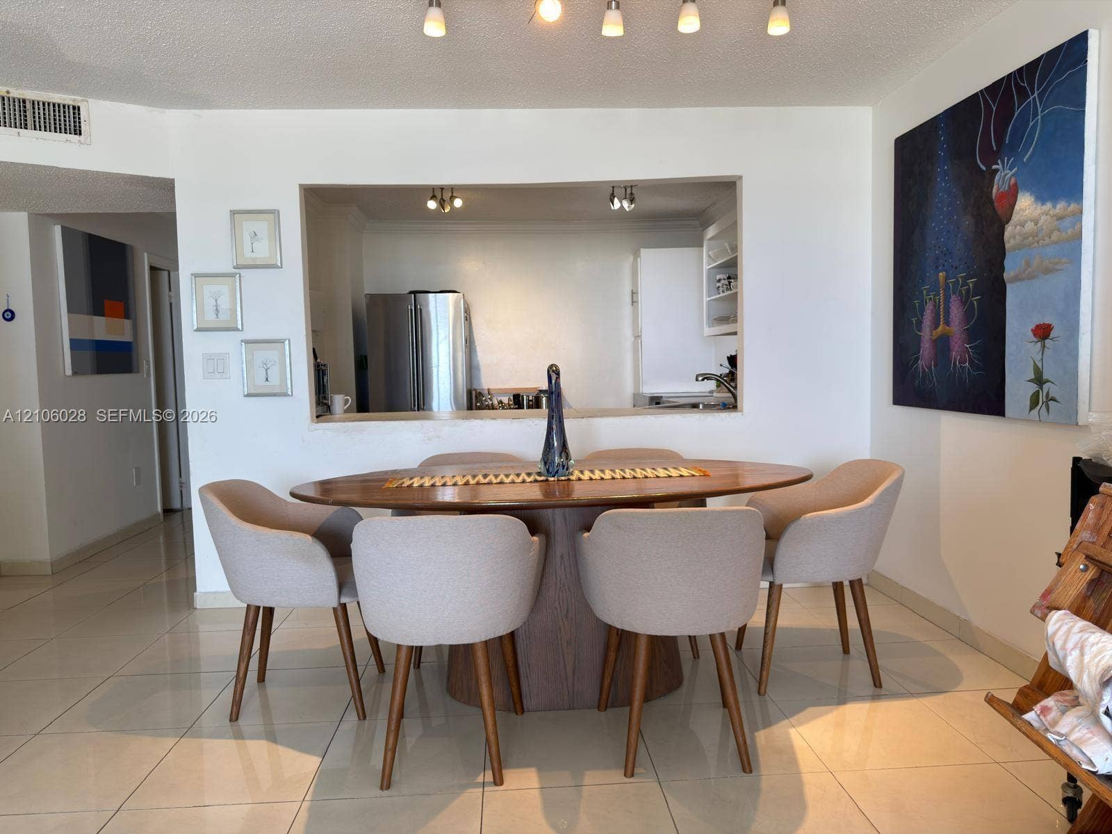 2780 NE 183rd Street, #1605, Aventura, FL 33160 Interior space featuring neutral tile flooring, five-light track lighting, and a pass-through opening to the kitchen