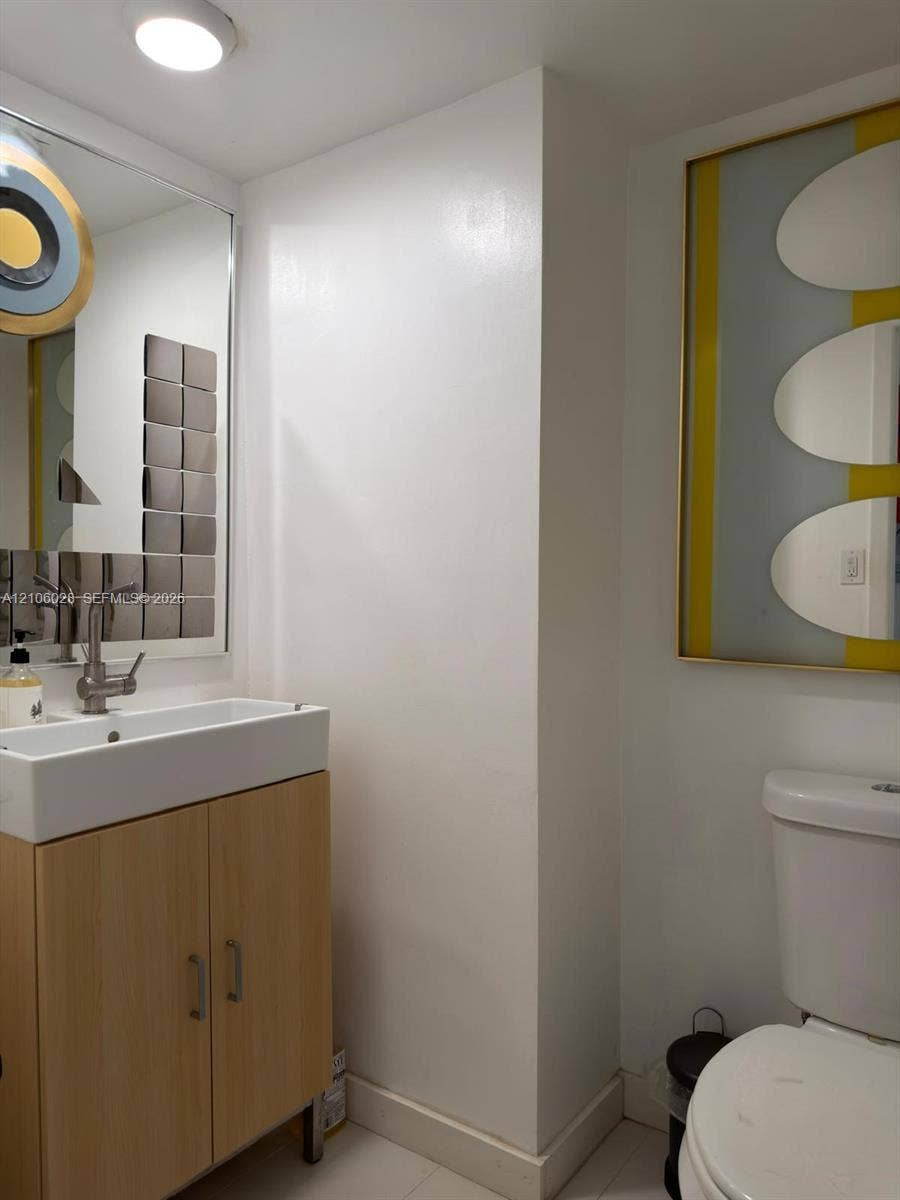 2780 NE 183rd Street, #1605, Aventura, FL 33160 Bathroom featuring a light-wood vanity cabinet, rectangular ceramic vessel sink, sleek metallic faucet, and a large wall-mounted mirror