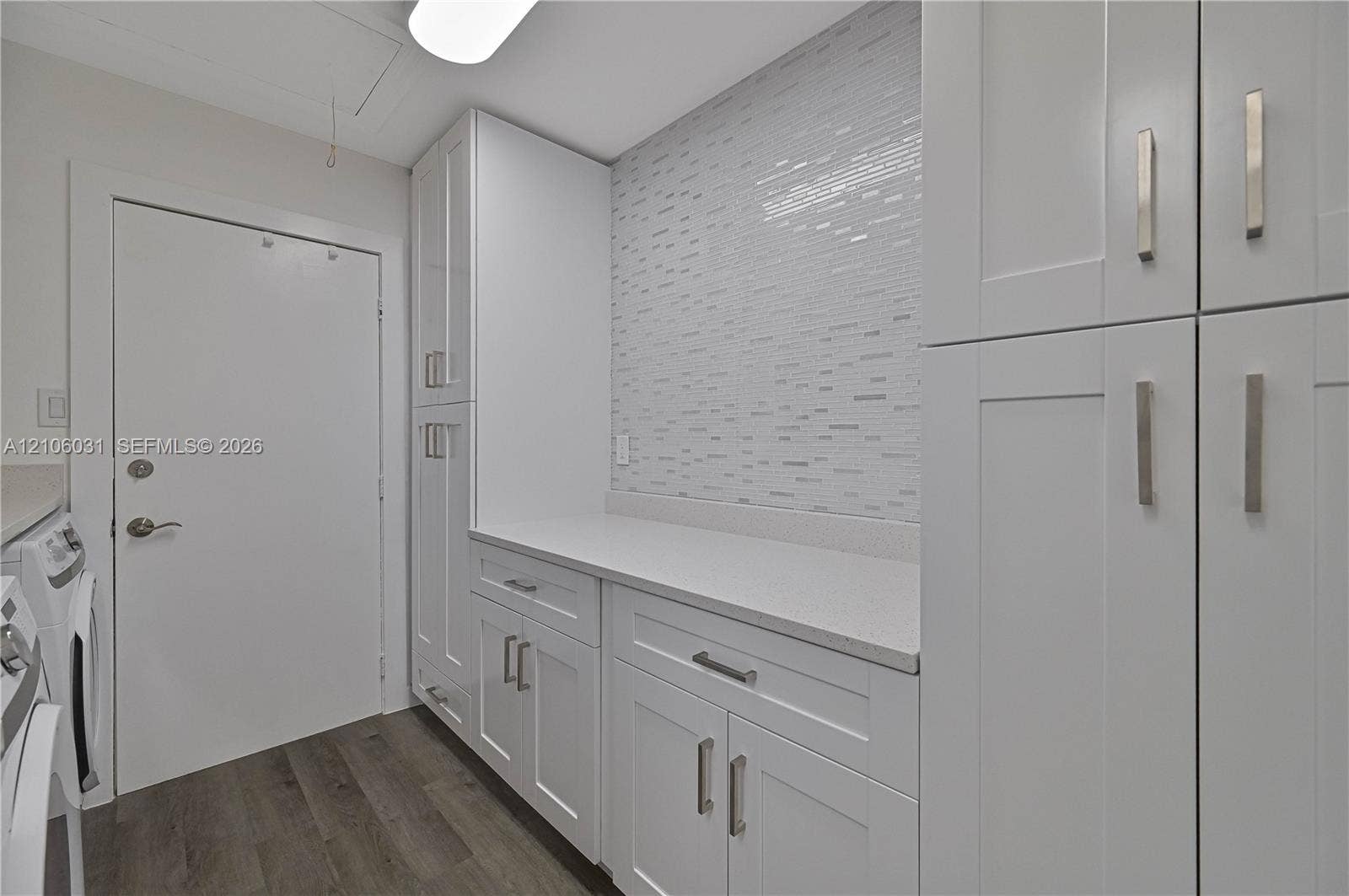 1106 SE 23rd Place, Cape Coral, FL 33990 White shaker-style cabinetry with satin nickel pulls, quartz countertops, mosaic tile backsplash, and wood-finish flooring