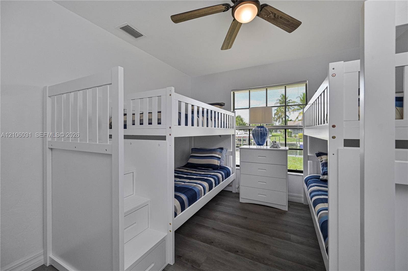 1106 SE 23rd Place, Cape Coral, FL 33990 Room featuring wood-finish flooring, a multi-blade ceiling fan with integrated lighting, and a window with exterior water and landscape surroundings