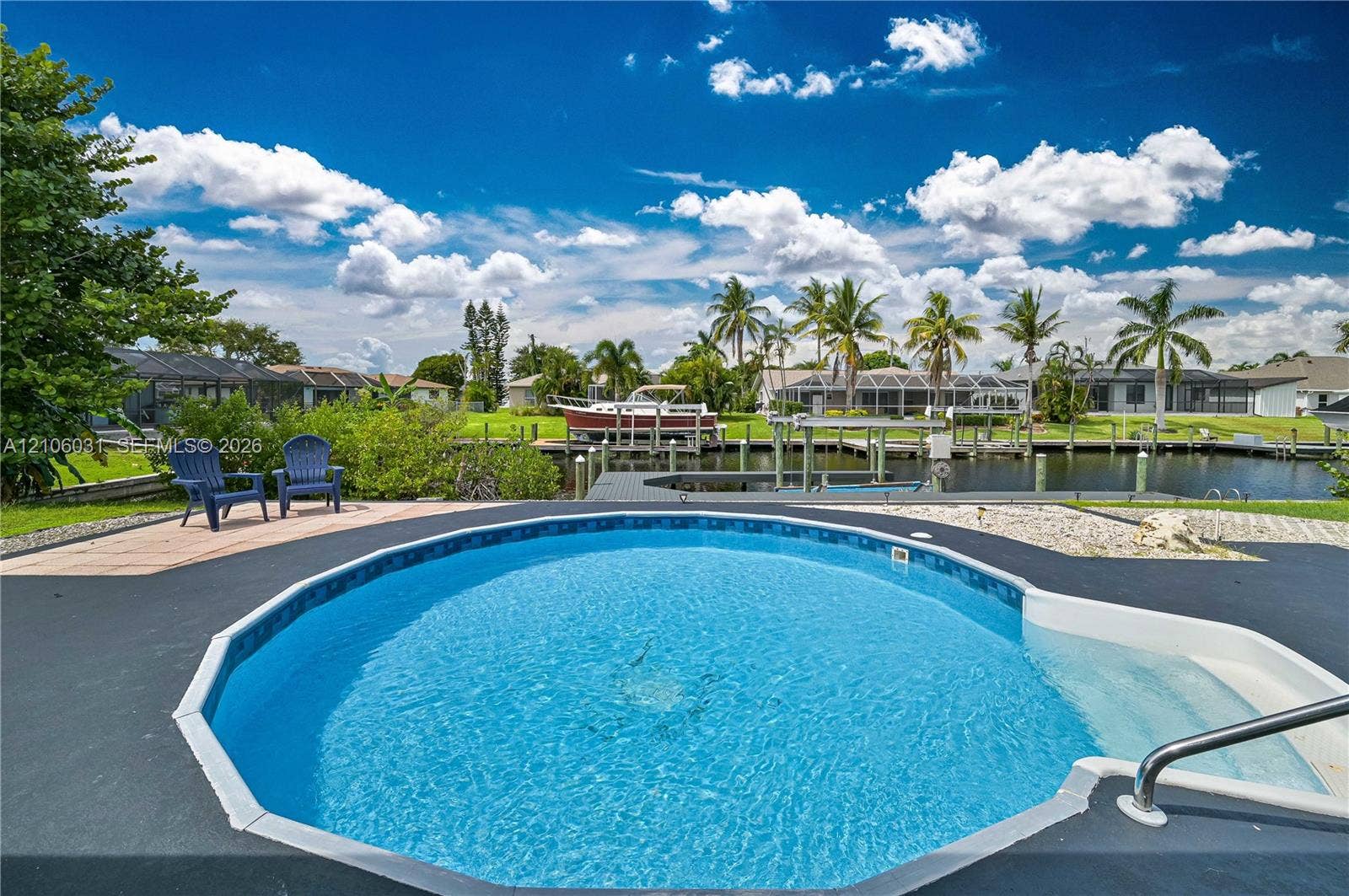 1106 SE 23rd Place, Cape Coral, FL 33990 In-ground pool with integrated steps, canal frontage, private boat dock, and paved poolside patio