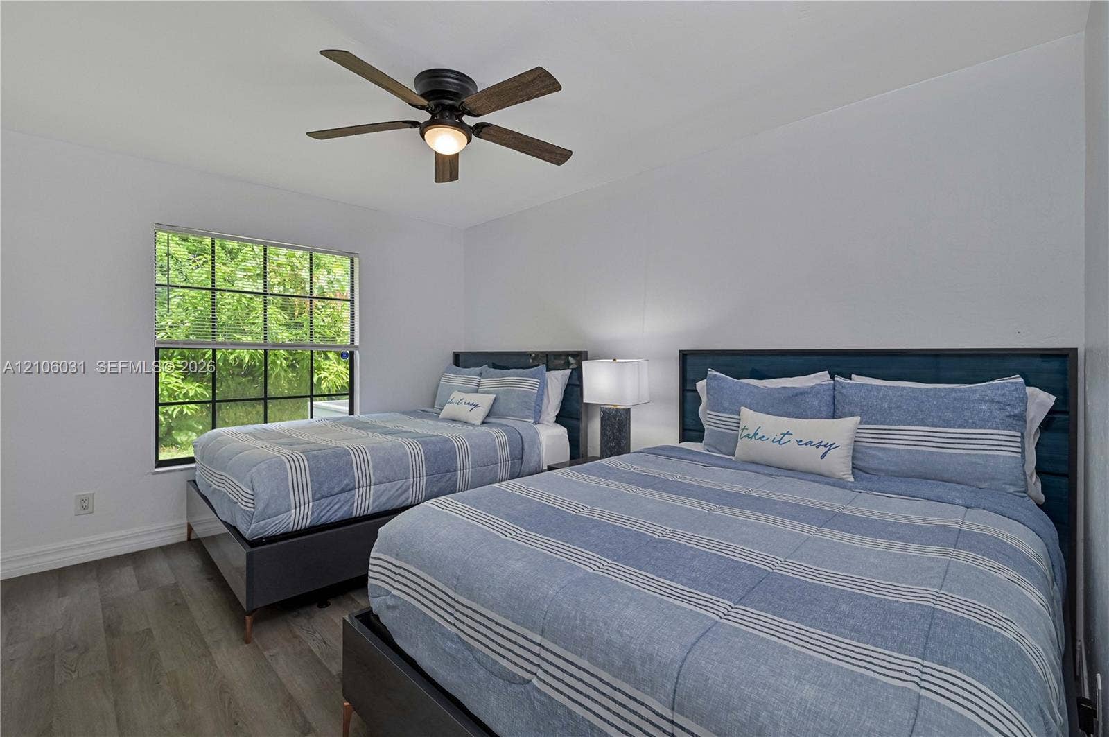1106 SE 23rd Place, Cape Coral, FL 33990 Interior space featuring wood-finish flooring, a multi-pane window with dark framing, and a ceiling-mounted fan with integrated light fixture