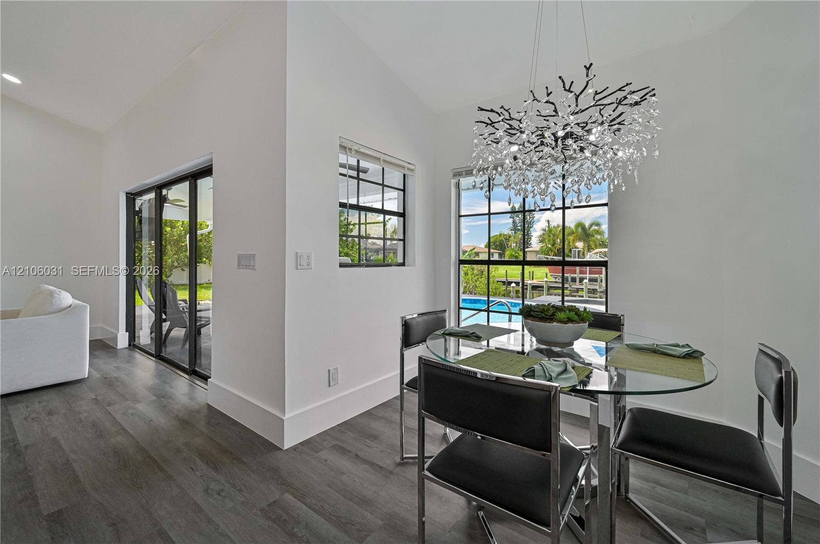 1106 SE 23rd Place, Cape Coral, FL 33990 Wood-finish flooring, floor-to-ceiling grid windows, sliding glass door, and decorative branching chandelier