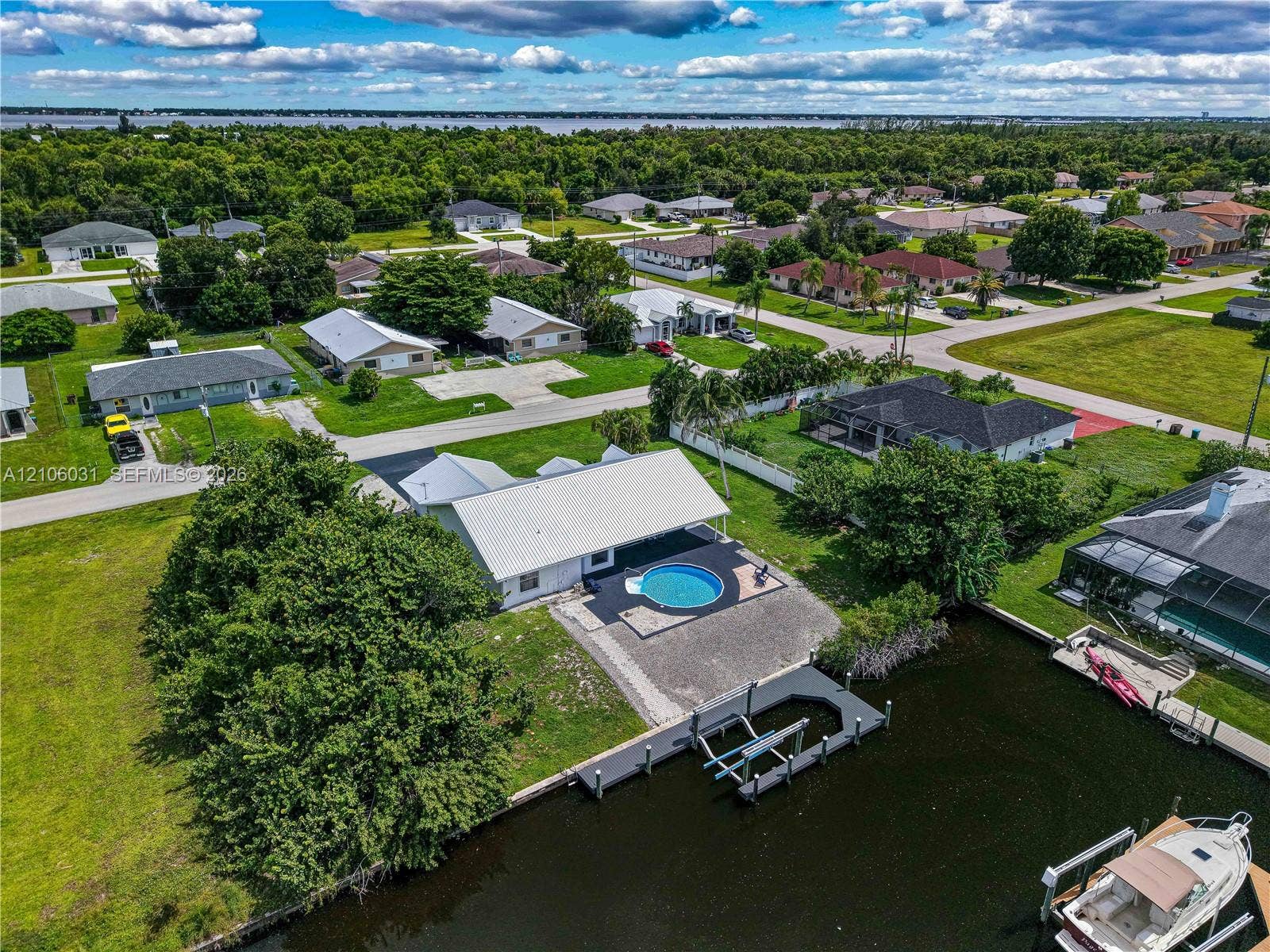 1106 SE 23rd Place, Cape Coral, FL 33990 Waterfront property featuring a private boat dock, built-in swimming pool, paved patio, and canal access