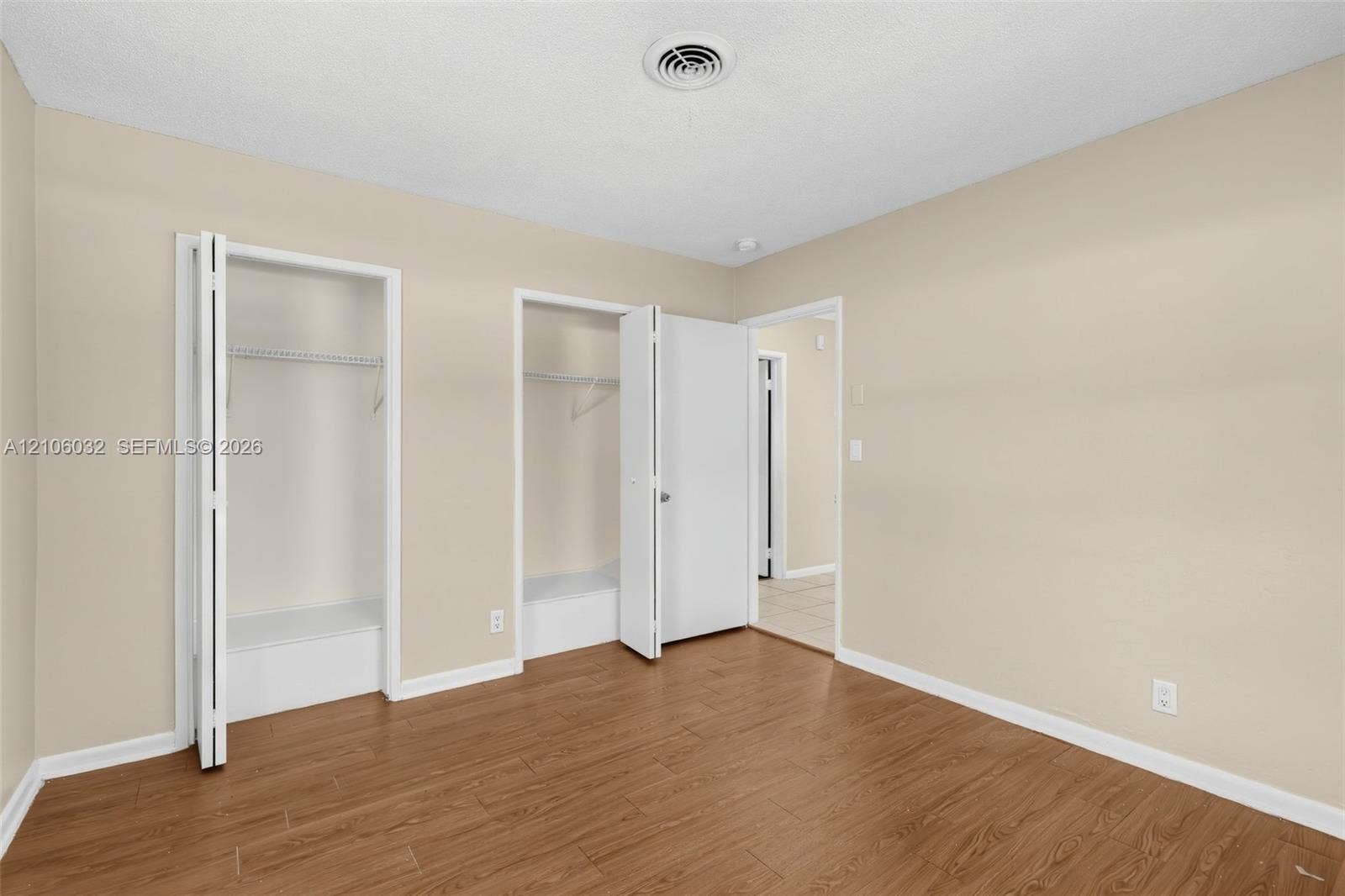 759 NW 7th Street, Boca Raton, FL 33486 Wood-finish flooring, neutral wall tones, and dual closets featuring white doors and integrated shelving