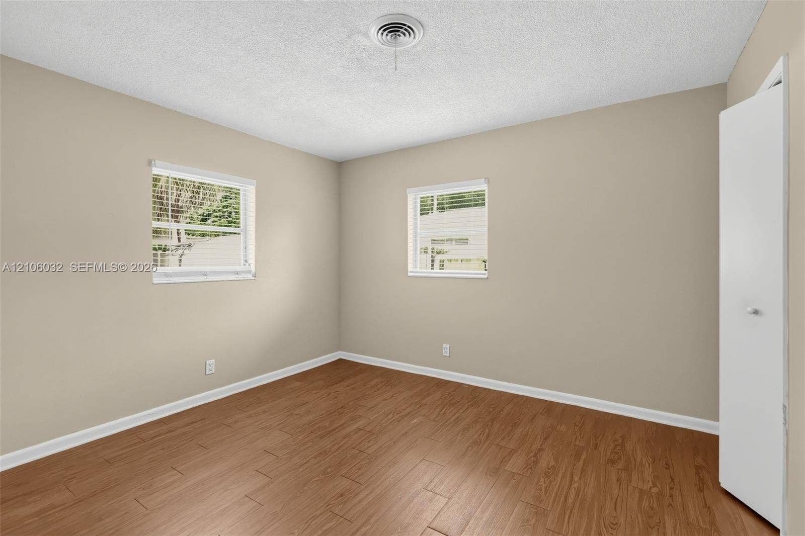 759 NW 7th Street, Boca Raton, FL 33486 Neutral wall tones, wood-finish flooring, two dual-pane windows, and a built-in closet with a white panel door