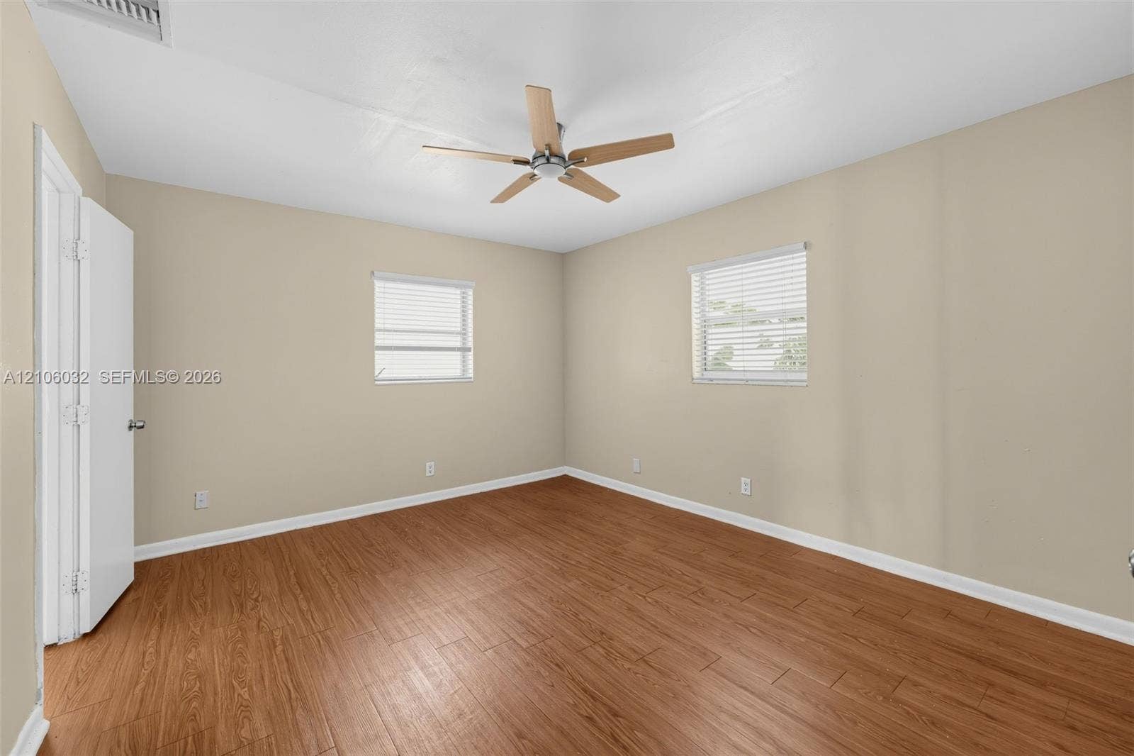 759 NW 7th Street, Boca Raton, FL 33486 Wood-finish flooring, neutral wall paint, two windows with horizontal blinds, and a multi-blade ceiling fan