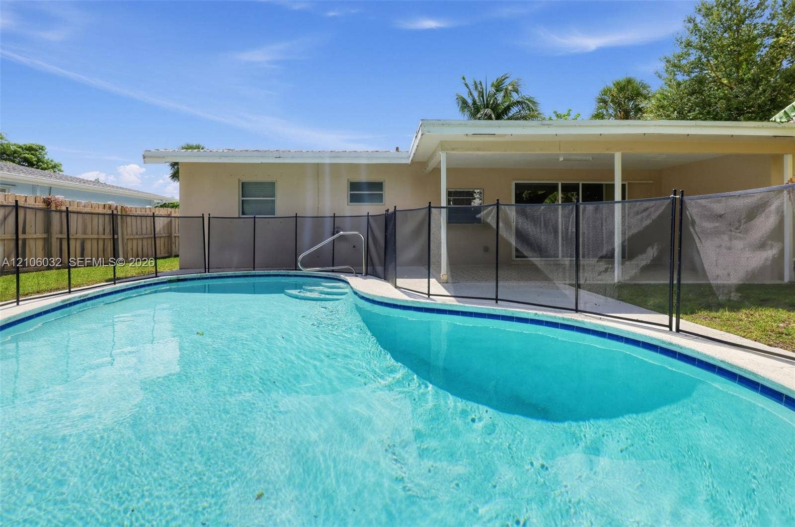 759 NW 7th Street, Boca Raton, FL 33486 In-ground swimming pool featuring a mesh safety fence, concrete pool deck, and a covered rear patio