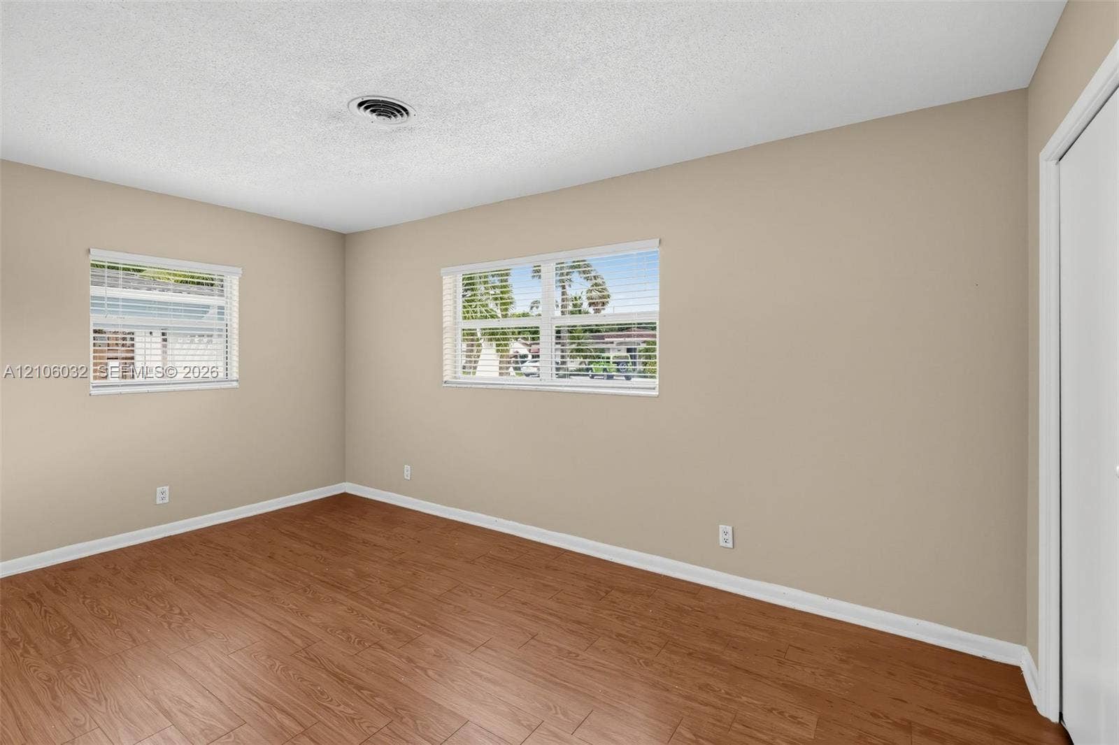 759 NW 7th Street, Boca Raton, FL 33486 Room featuring wood-finish flooring, neutral wall paint, two dual-pane windows, and a closet with a door