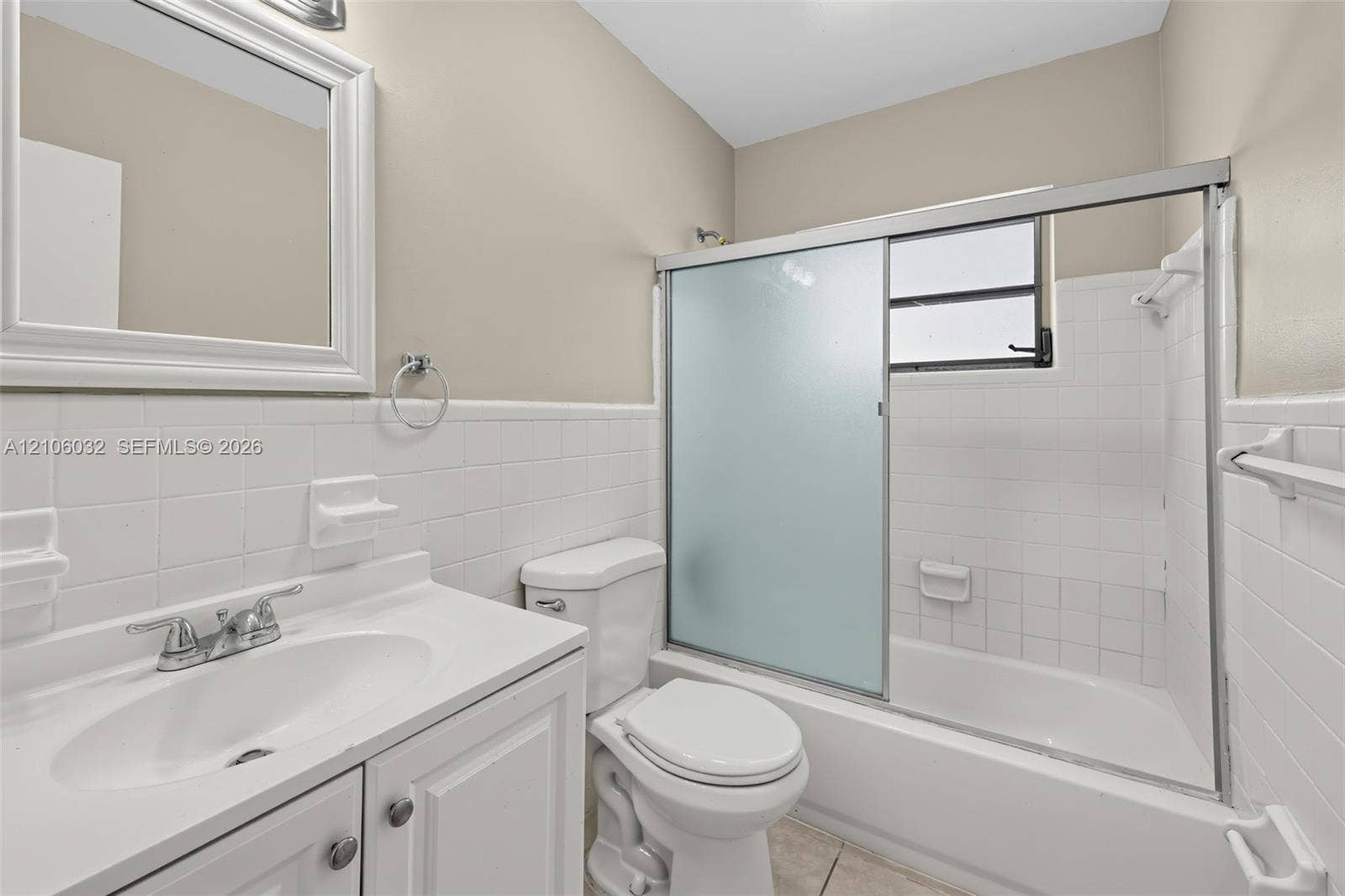 759 NW 7th Street, Boca Raton, FL 33486 Bathroom featuring a white vanity with integrated basin, framed wall mirror, and tub-shower combination with sliding frosted glass doors and tile surround