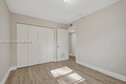 1471 NW 22nd Court, #2, Fort Lauderdale, Fort Lauderdale, FL 33311 Neutral-toned interior featuring wood-finish flooring, white four-panel closet doors, a matching interior door with a round hardware pull, and a flush-mount ceiling light fixture