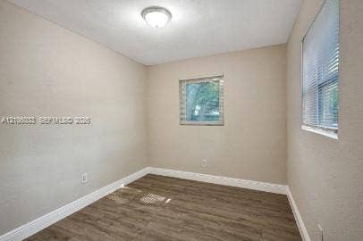 1471 NW 22nd Court, #2, Fort Lauderdale, Fort Lauderdale, FL 33311 Interior space featuring wood-finish flooring, neutral wall tones, two windows with horizontal blinds, and a flush-mount ceiling light fixture