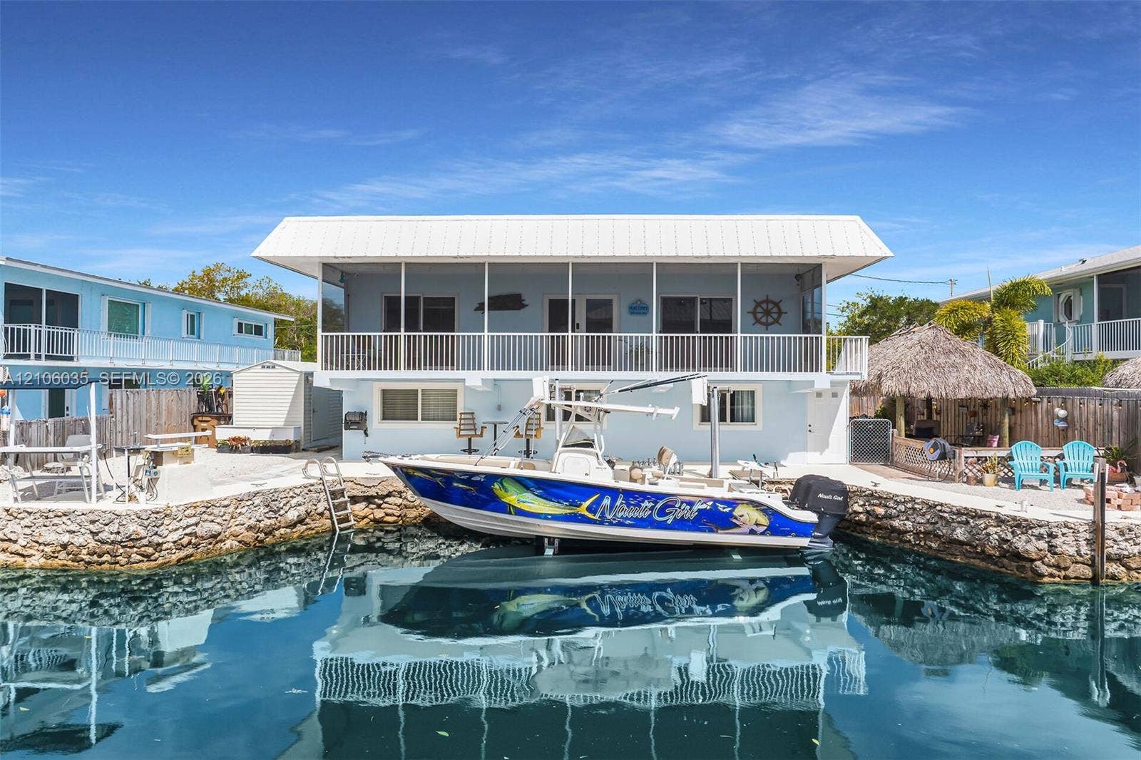 128 Dove Avenue, Tavernier, FL 33070 Waterfront residence featuring a private stone-lined seawall, integrated boat slip, elevated screened-in porch, and metal roofing