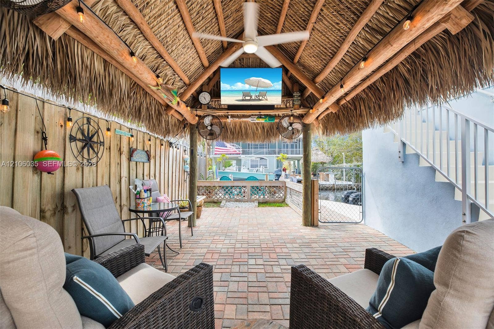 128 Dove Avenue, Tavernier, FL 33070 Covered patio featuring a thatched roof, brick paver flooring, ceiling fan, and string lighting