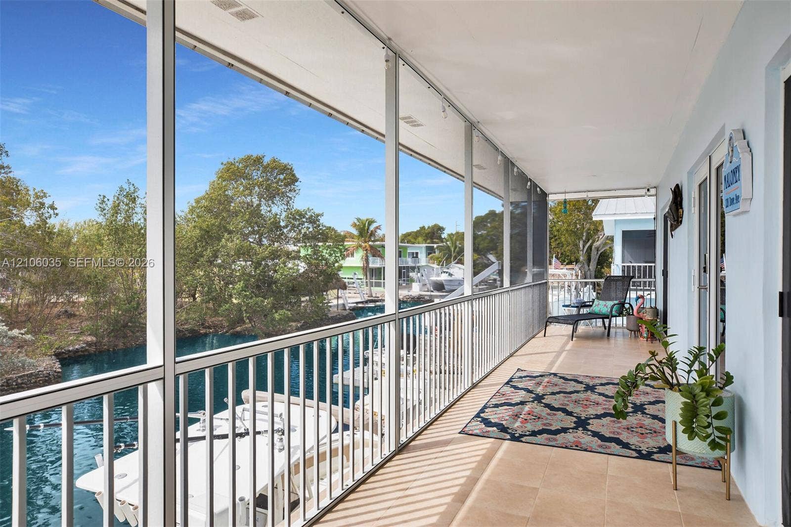128 Dove Avenue, Tavernier, FL 33070 Covered screened-in balcony featuring tile flooring and metal railings, overlooking a canal with private dock access