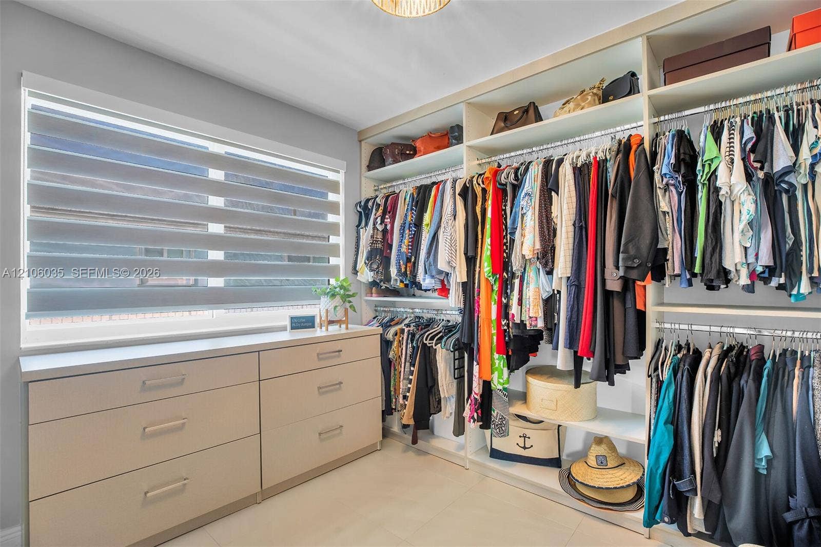 128 Dove Avenue, Tavernier, FL 33070 Custom walk-in closet featuring extensive built-in shelving, hanging rods, integrated drawer storage, and a light-filtering window shade