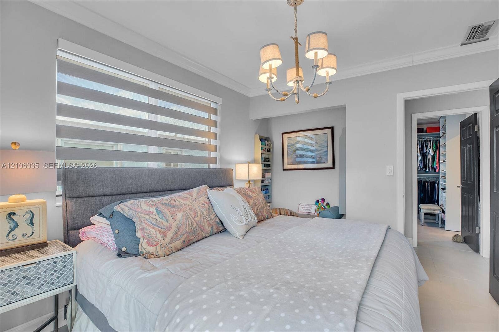 128 Dove Avenue, Tavernier, FL 33070 Neutral-toned bedroom featuring crown molding, a five-arm metal chandelier, and layered dual-fabric window shades