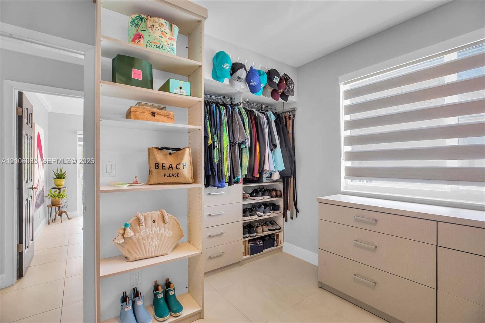 128 Dove Avenue, Tavernier, FL 33070 Custom closet organization system featuring light-toned cabinetry, integrated shelving units, tiered storage drawers, and a window fitted with adjustable dual-layer shades