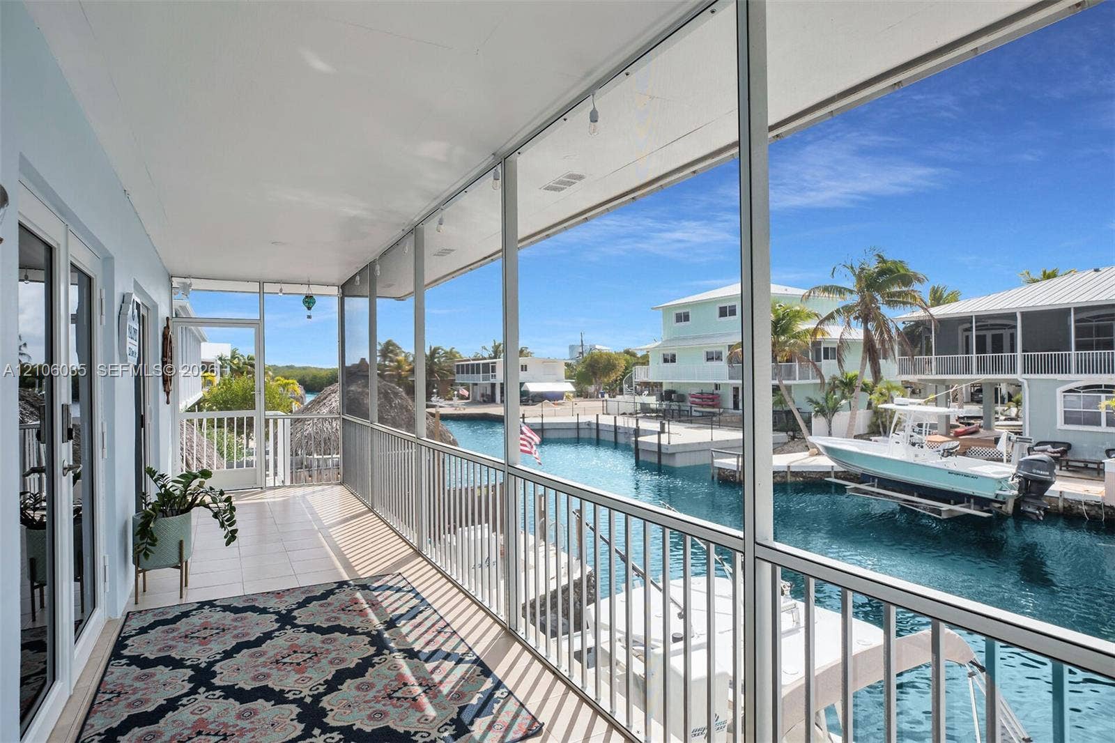 128 Dove Avenue, Tavernier, FL 33070 Screened-in balcony featuring tile flooring, metal railings, and direct water canal access