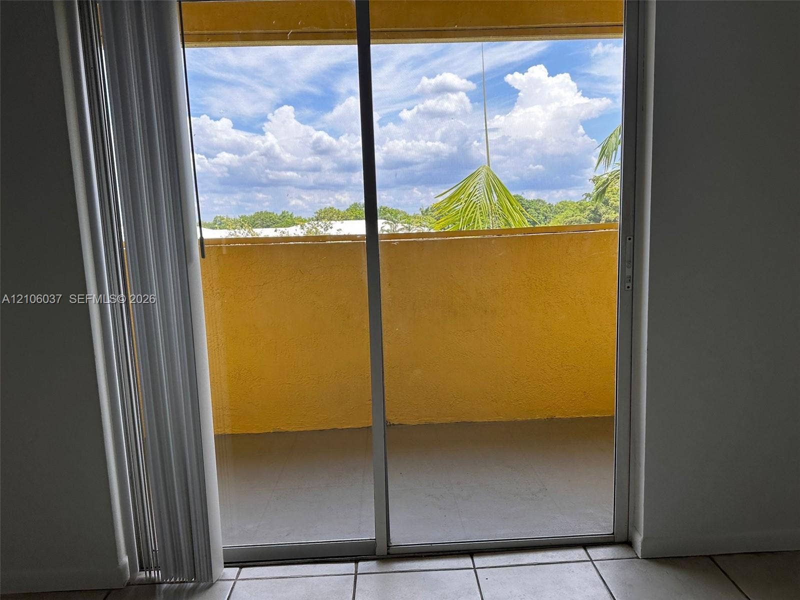 14951 SW 82nd Lane, #17-504, Miami, FL 33193 Sliding glass door opening to a private balcony with solid masonry railings and ceramic tile flooring