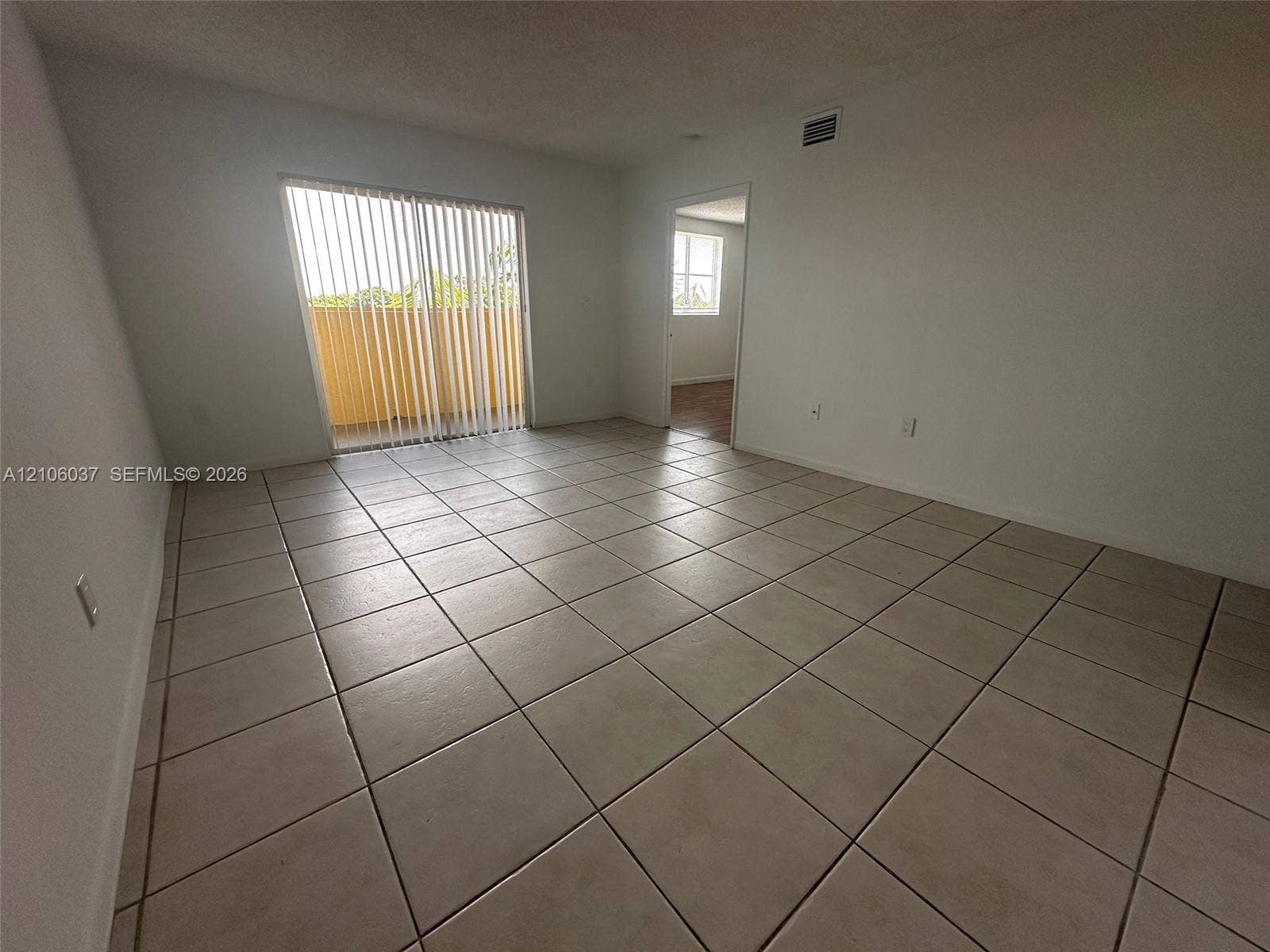 14951 SW 82nd Lane, #17-504, Miami, FL 33193 Interior room featuring large-format ceramic floor tile, sliding glass door with vertical blinds, and neutral wall tones