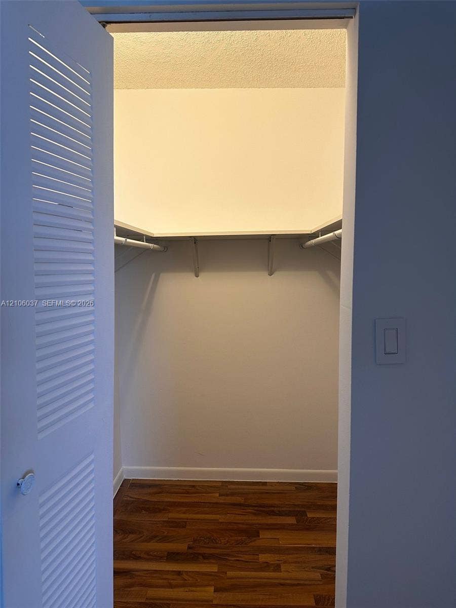 14951 SW 82nd Lane, #17-504, Miami, FL 33193 Storage space featuring louvered bi-fold doors, white shelving, a rod for hanging items, and wood-finish flooring