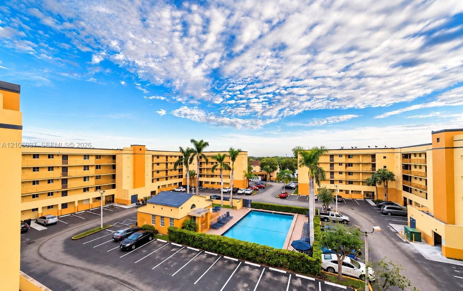 14951 SW 82nd Lane, #17-504, Miami, FL 33193 Multi-story residential complex featuring an outdoor swimming pool, paved surface parking, and mature palm trees