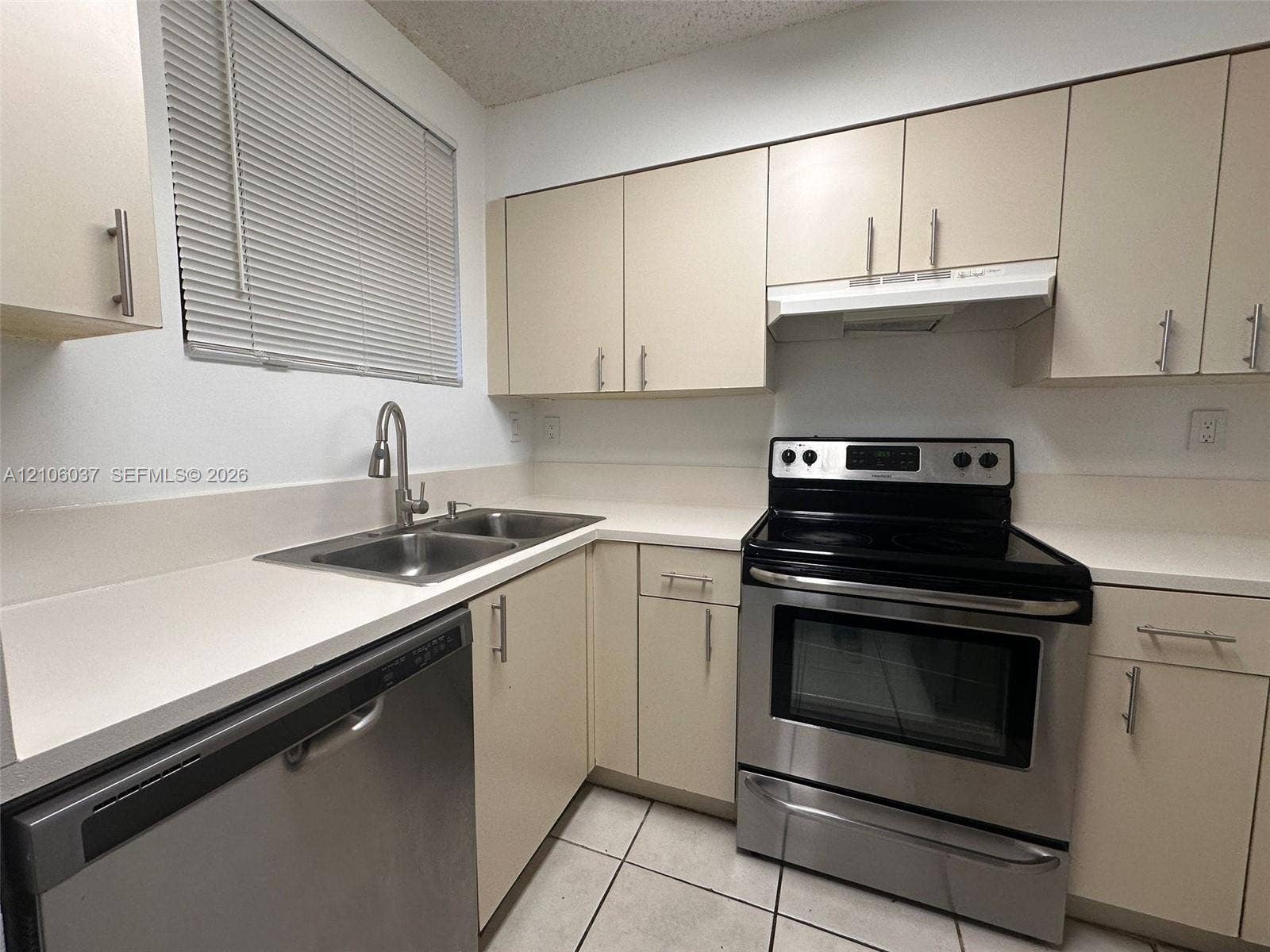 14951 SW 82nd Lane, #17-504, Miami, FL 33193 Kitchen featuring neutral flat-panel cabinetry, solid surface countertops, stainless steel appliances, a dual-basin sink with a gooseneck faucet, and tiled flooring