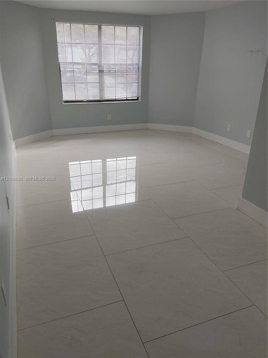 Neutral-toned room featuring large-format polished tile flooring and a multi-pane window