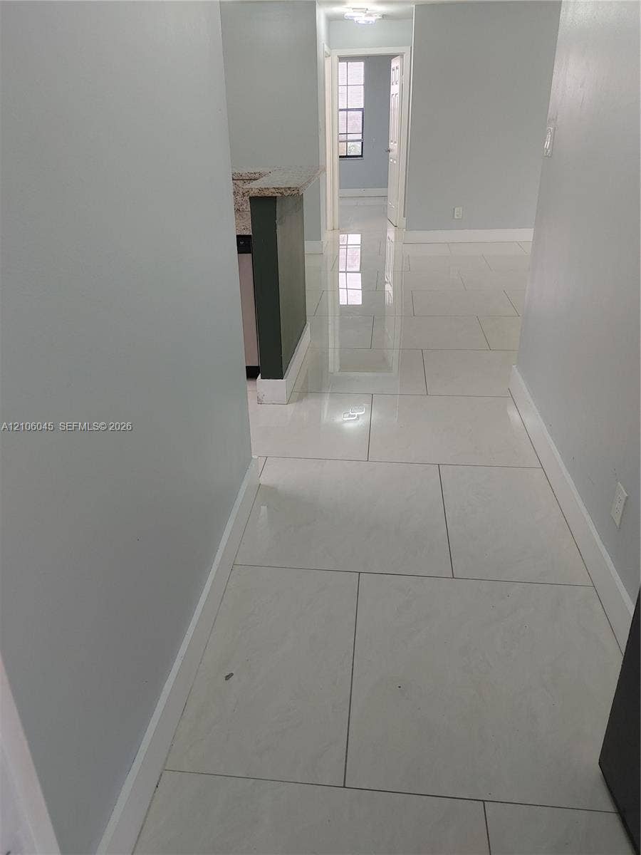 Large-format polished tile flooring featuring a neutral finish and a peninsula with a stone-composite countertop