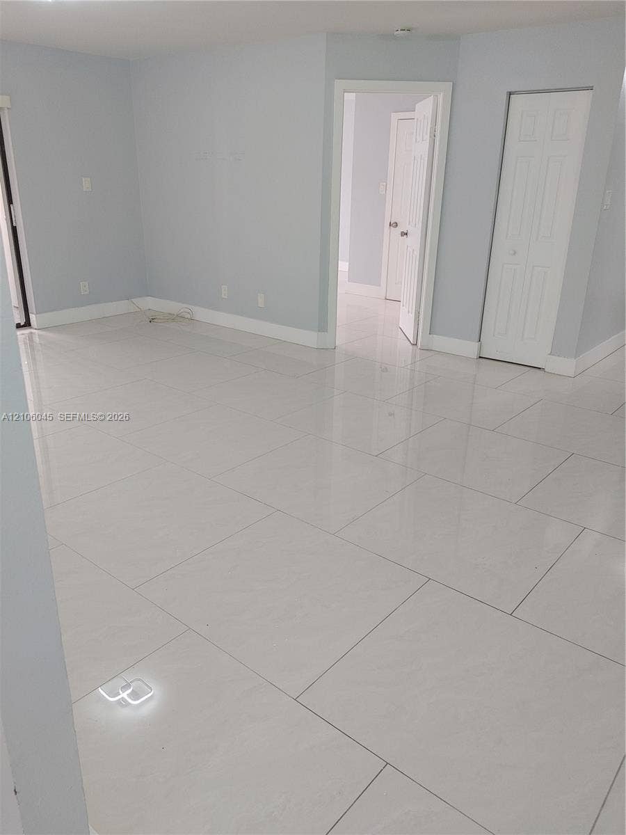 Large-format white tile flooring, neutral wall tones, and two-panel interior doors