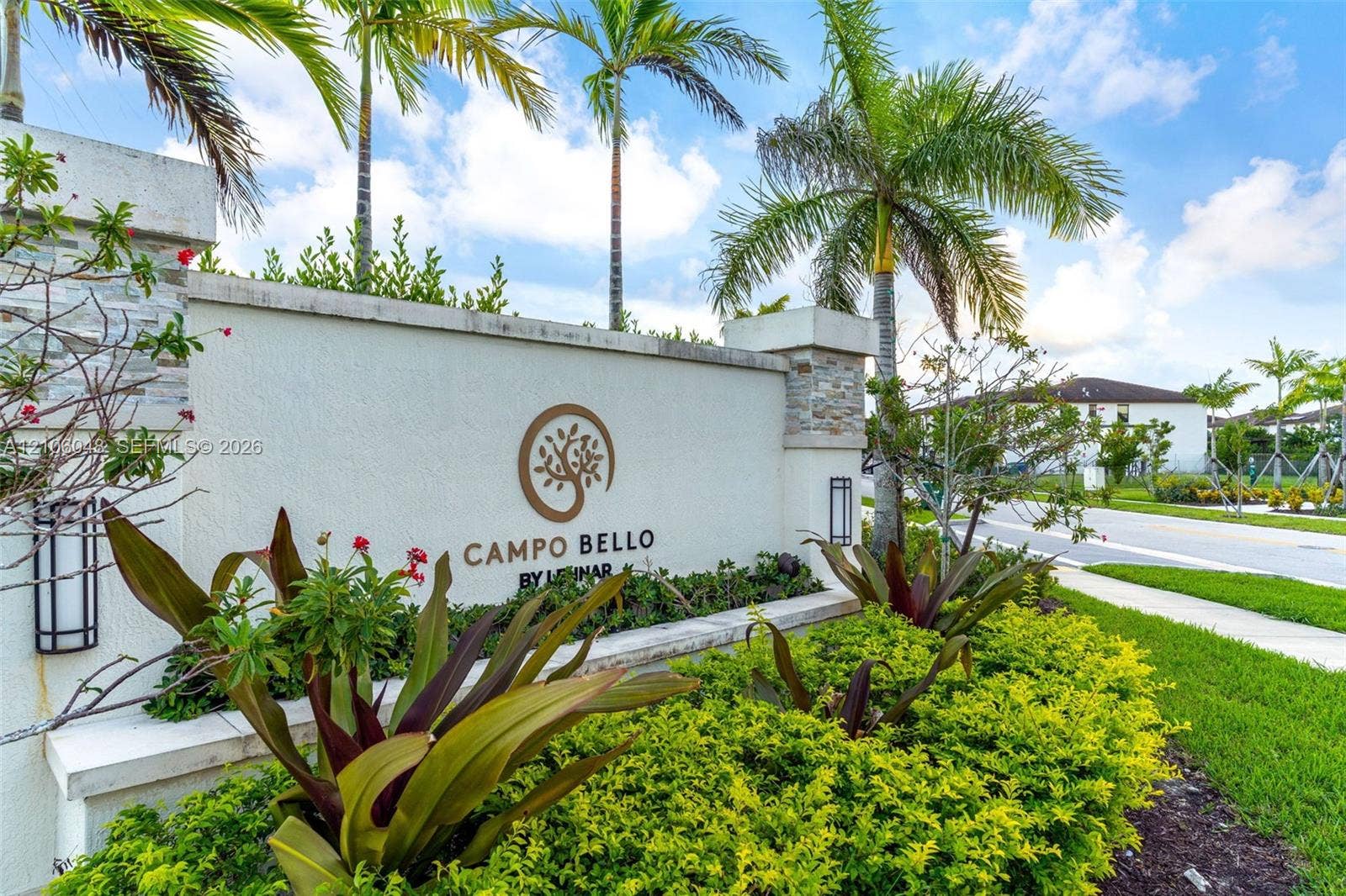 25134 SW 108th Court, Homestead, FL 33032 Stucco monument signage featuring stone pillar accents, integrated wall-mounted lighting, and professional landscape design with mature palm trees