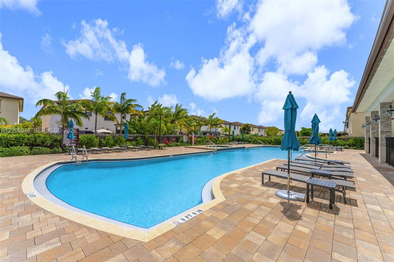 25134 SW 108th Court, Homestead, FL 33032 Swimming pool featuring a paver deck, metal railings, and stone-accented exterior building facade