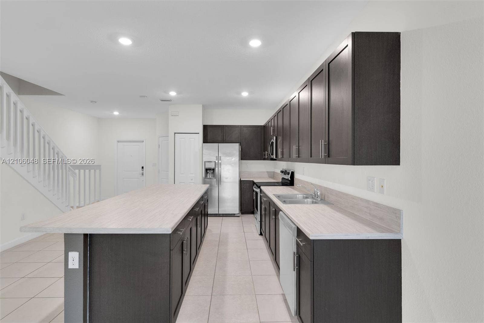 25134 SW 108th Court, Homestead, FL 33032 Kitchen featuring dark cabinetry, expansive center island, light-toned laminate countertops, stainless steel appliances, and ceramic tile flooring