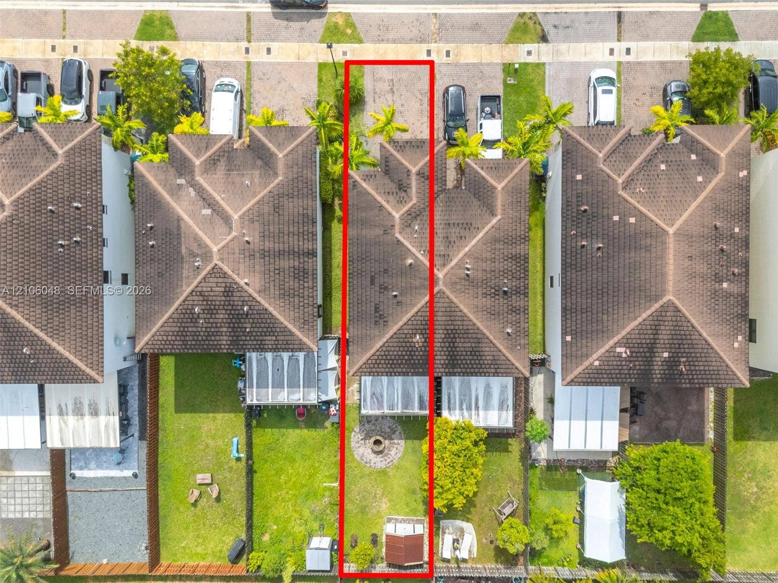 25134 SW 108th Court, Homestead, FL 33032 Aerial perspective of a detached residential property featuring a hipped roof, a screened-in rear patio, a stone-paved fire pit area, and a fenced backyard