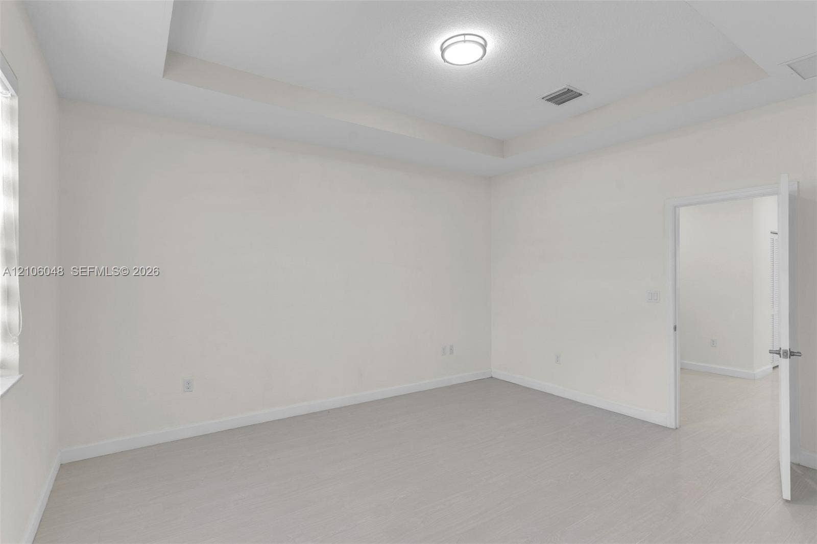 25134 SW 108th Court, Homestead, FL 33032 Tray ceiling featuring a central flush-mount light fixture and wood-finish flooring