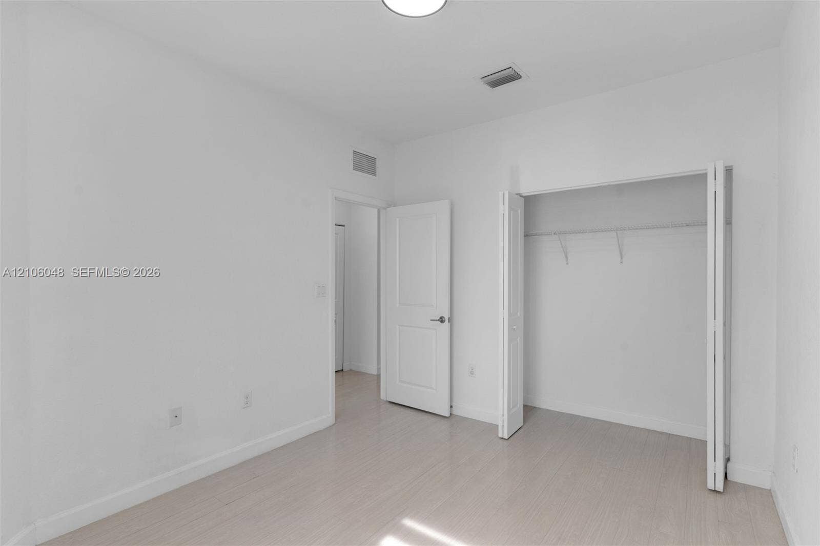 25134 SW 108th Court, Homestead, FL 33032 Interior space featuring light-toned wood-finish flooring, white walls, a closet with bifold doors, and a solid-core interior door