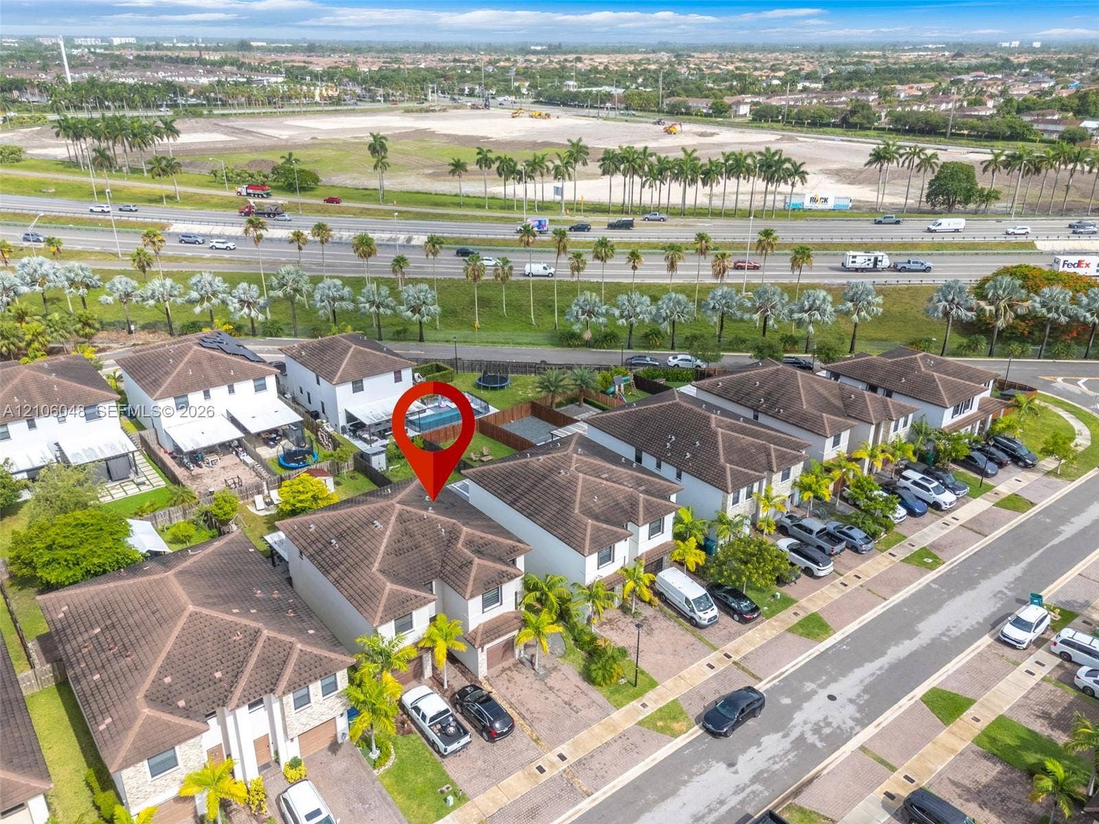 25134 SW 108th Court, Homestead, FL 33032 Two-story residential property featuring a tiled hip roof, paved driveway, attached garage, and a private screened-in swimming pool