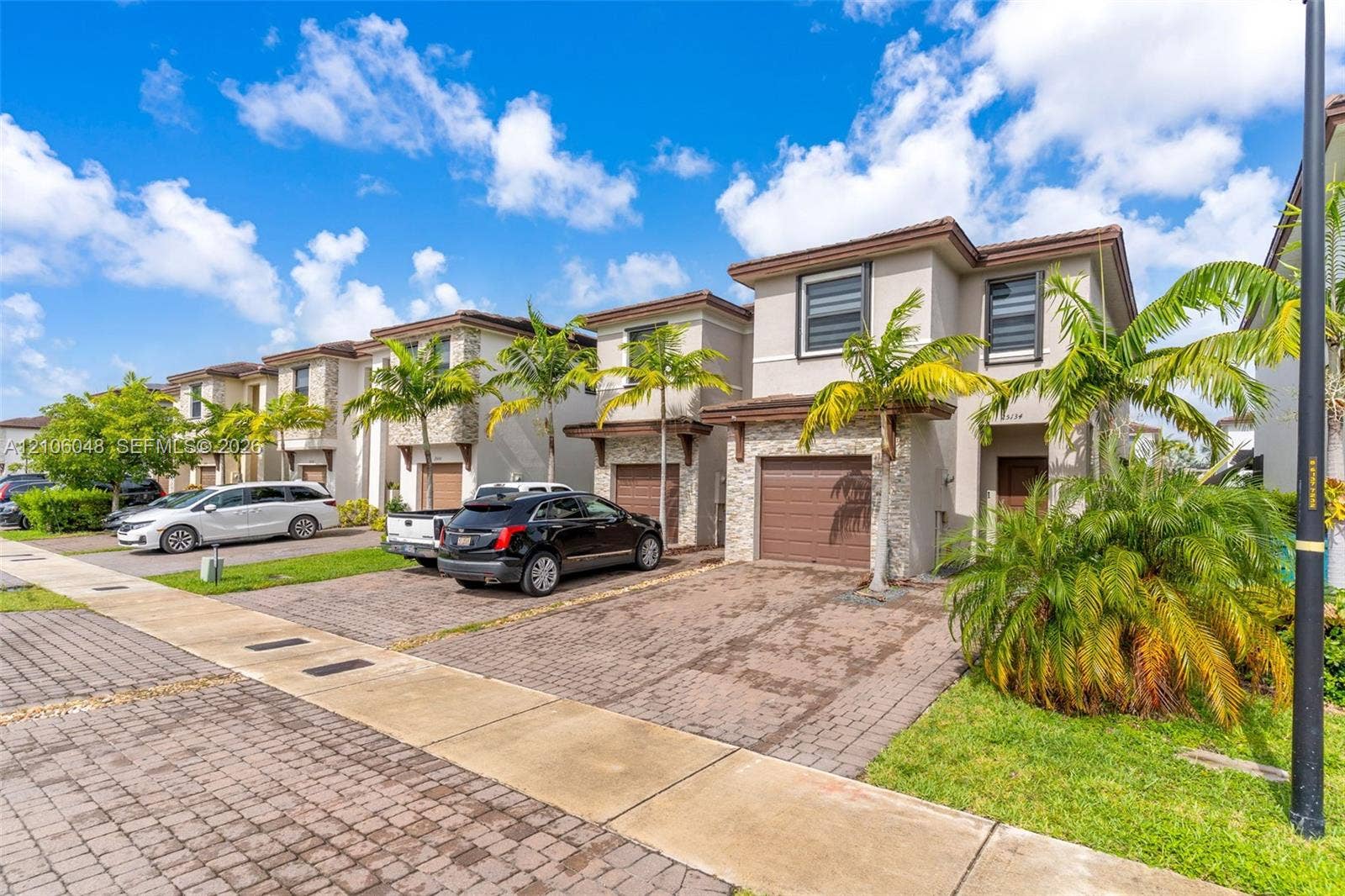 25134 SW 108th Court, Homestead, FL 33032 Two-story exterior featuring a stone veneer facade, a multi-paneled garage door, and paver driveways