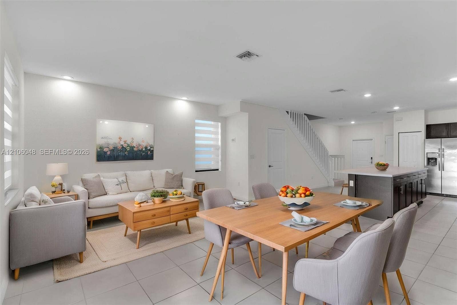 25134 SW 108th Court, Homestead, FL 33032 Open-concept interior featuring large-format tile flooring, recessed ceiling lighting, a kitchen island with stone countertops, and a white wooden staircase railing
