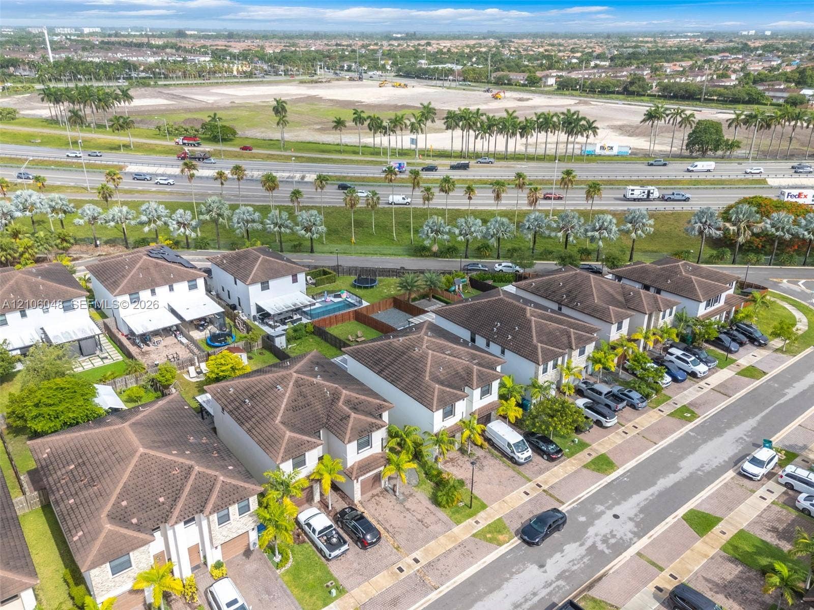 25134 SW 108th Court, Homestead, FL 33032 Aerial perspective of a multi-unit residential community featuring hipped roof structures, paved driveways, and landscaped palm trees