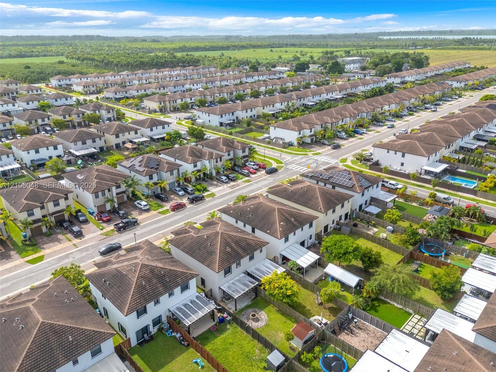 25134 SW 108th Court, Homestead, FL 33032 Aerial perspective of a planned residential community featuring two-story homes with hip roofs, paved street infrastructure, solar panel arrays, and enclosed backyards
