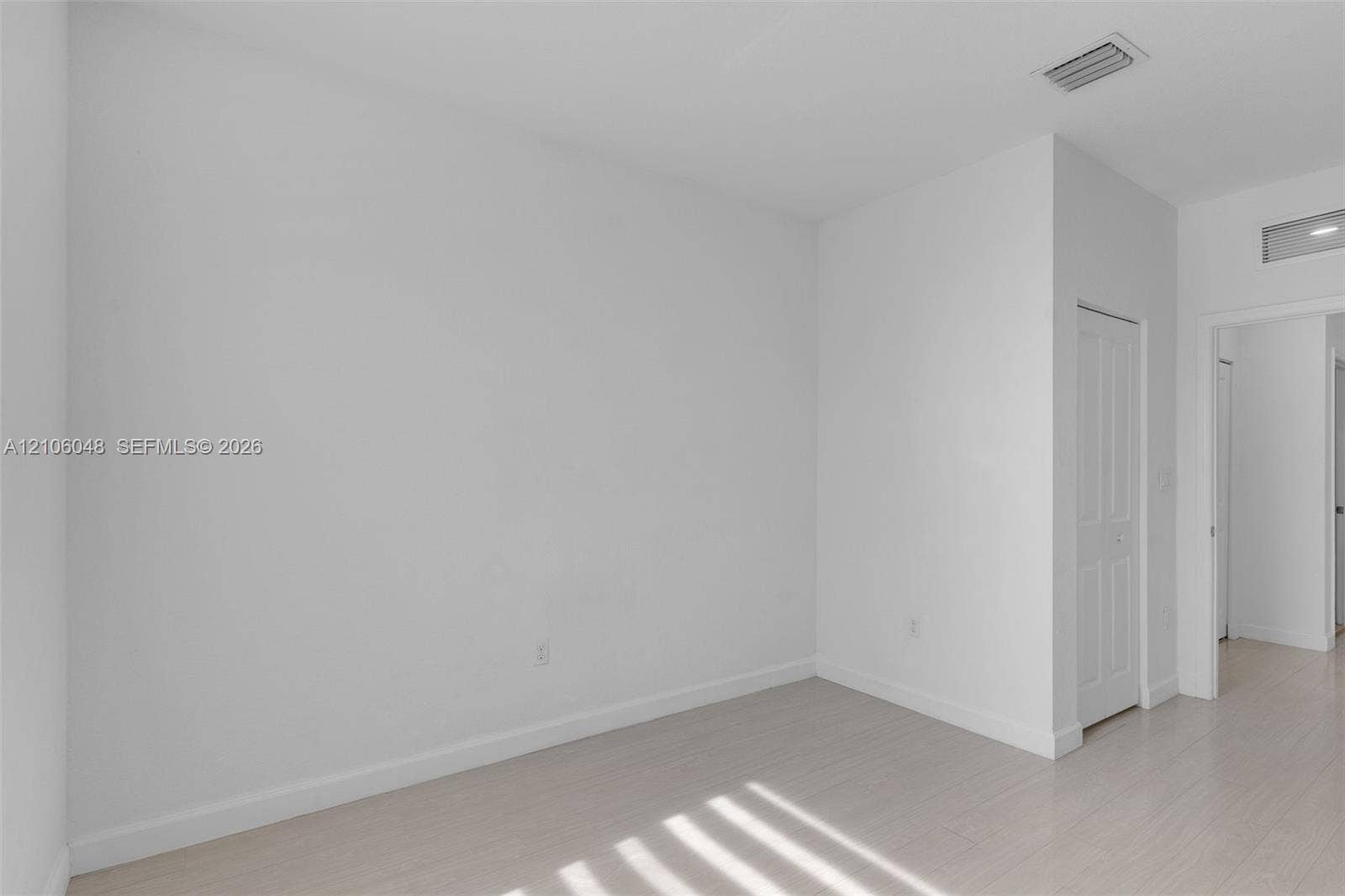 25134 SW 108th Court, Homestead, FL 33032 Neutral-toned interior space featuring light wood-finish flooring, smooth wall surfaces, and a multi-panel interior door