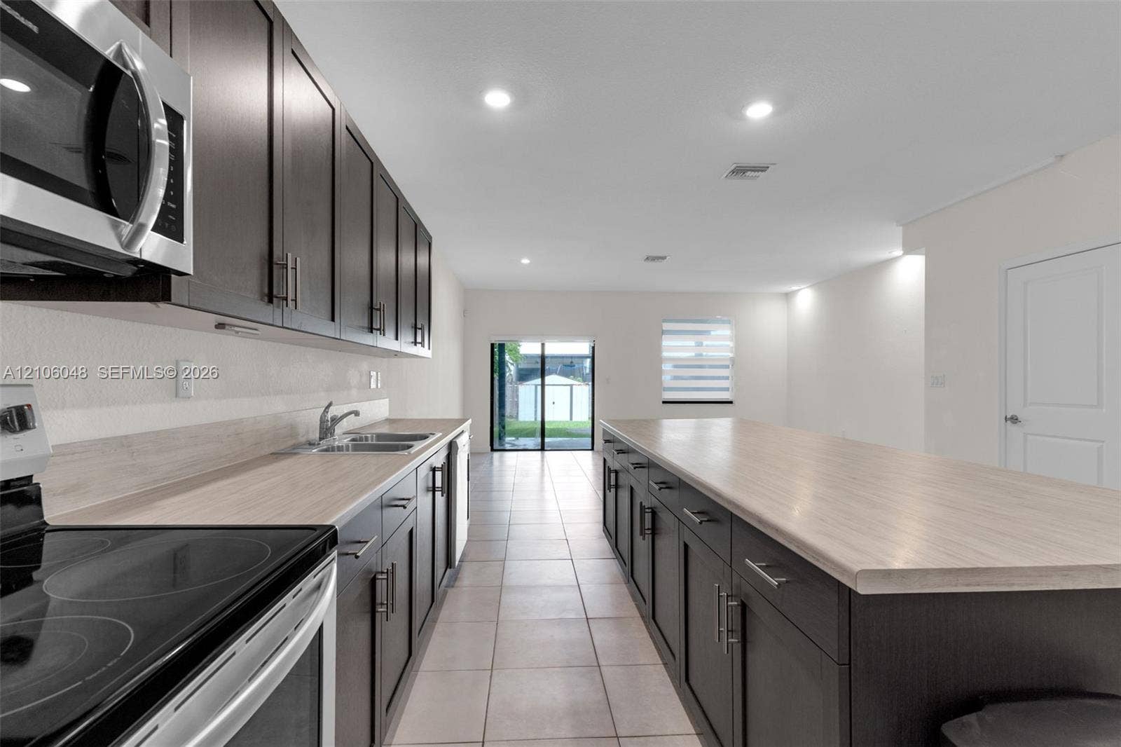 25134 SW 108th Court, Homestead, FL 33032 Kitchen featuring dark-finish cabinetry, light-tone countertops, stainless steel appliances, ceramic tile flooring, and a center island