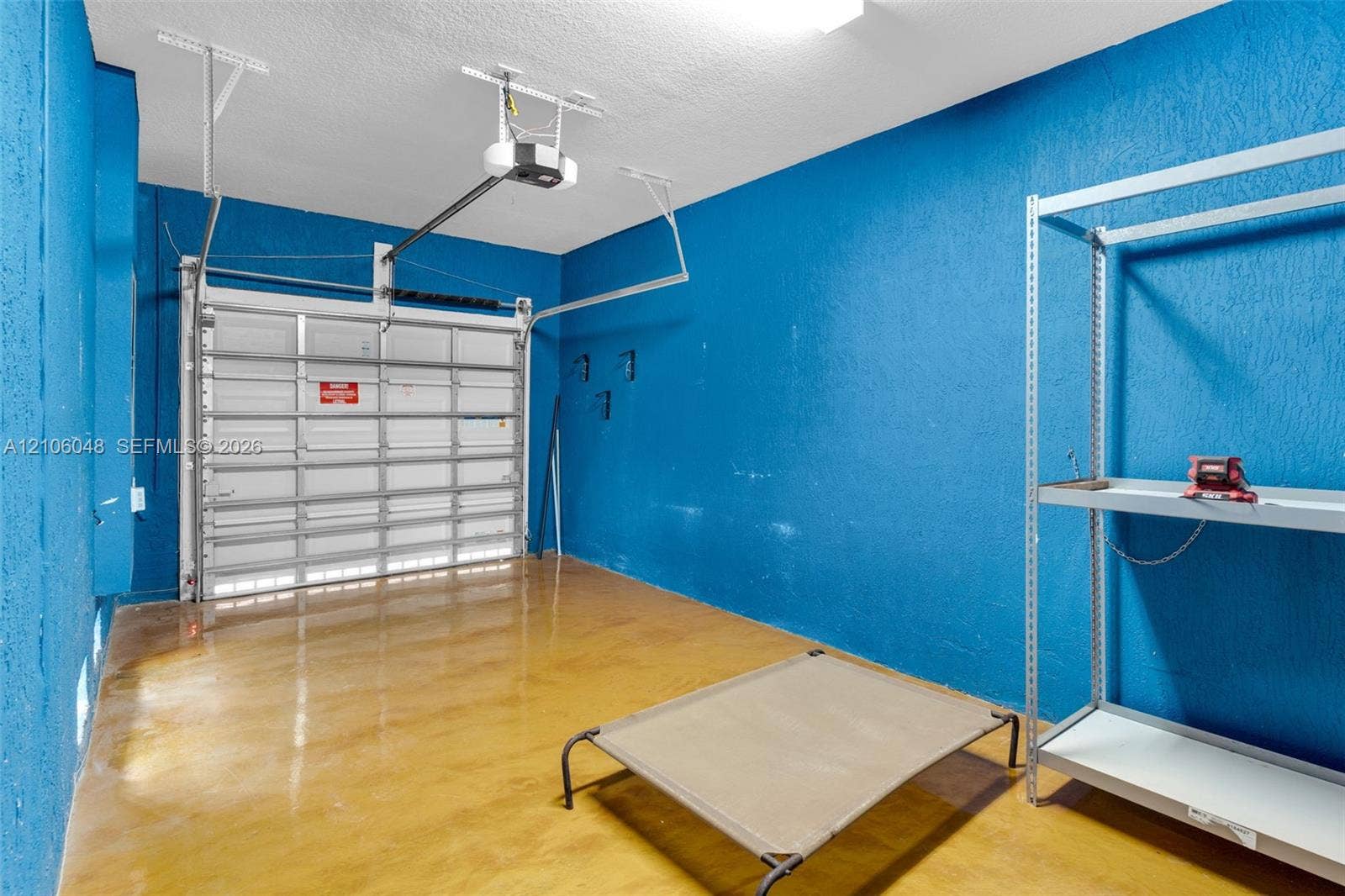 25134 SW 108th Court, Homestead, FL 33032 Garage space featuring high-gloss epoxy flooring, metal sectional garage door, and mounted automatic door opener