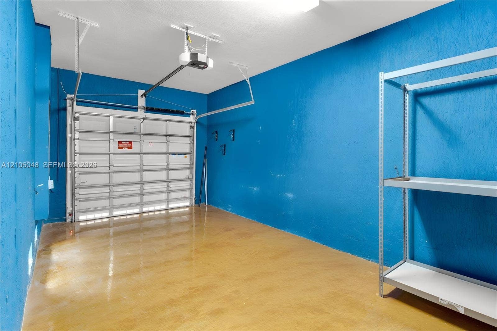 25134 SW 108th Court, Homestead, FL 33032 Garage featuring a sectional overhead door, automatic garage door opener, and finished concrete flooring