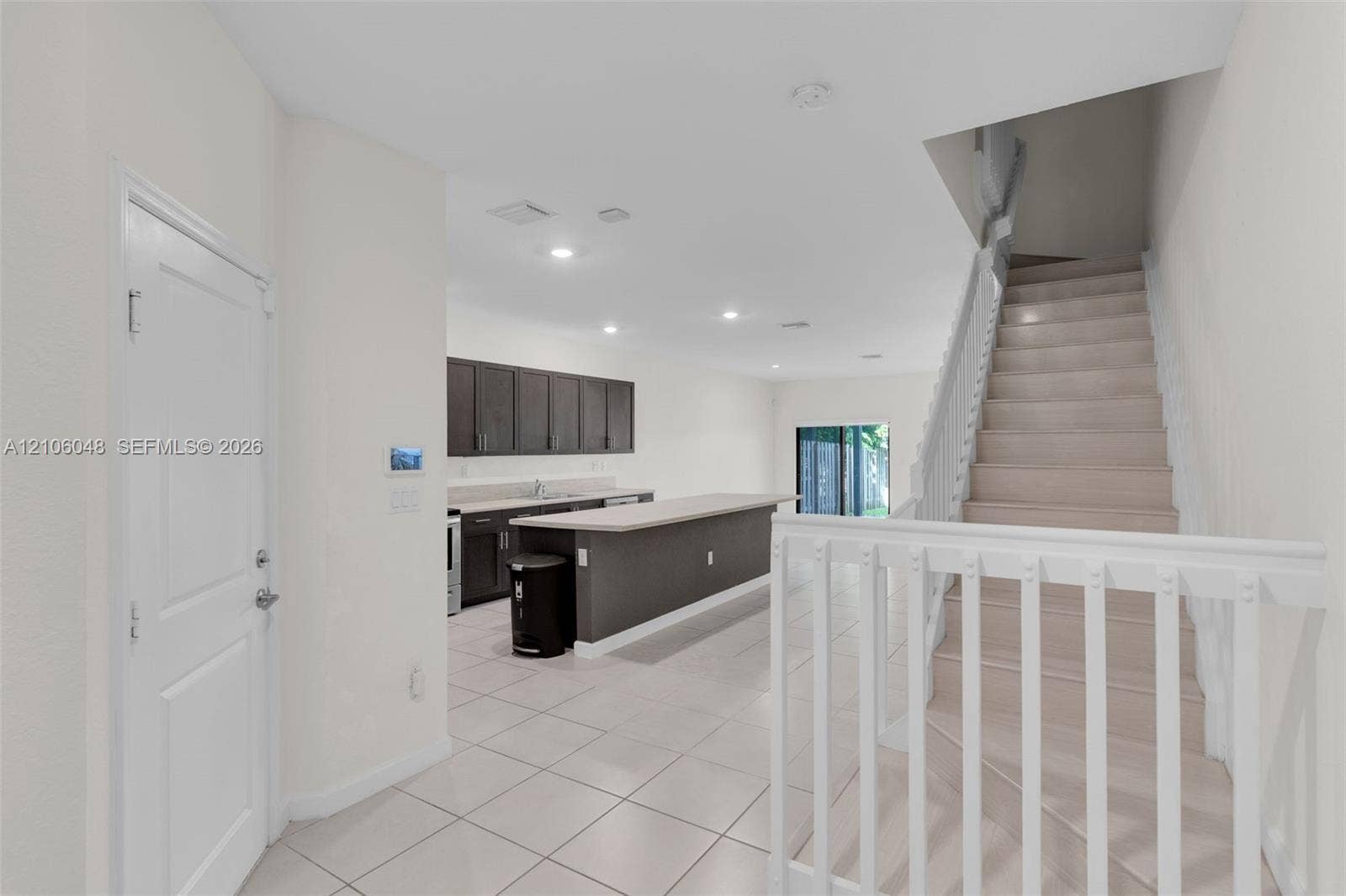 25134 SW 108th Court, Homestead, FL 33032 Kitchen featuring dark cabinetry, expansive countertop, and recessed lighting, complemented by tile flooring and white baluster staircase railing