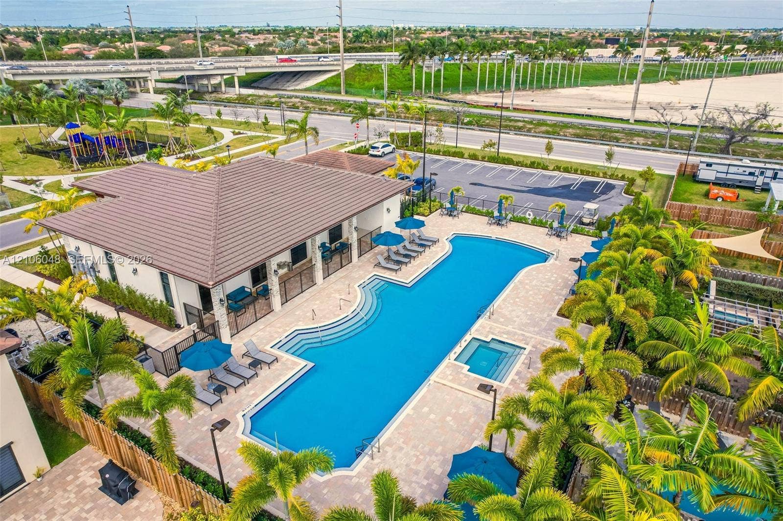 25134 SW 108th Court, Homestead, FL 33032 Community recreation facility featuring a resort-style swimming pool with integrated spa, paver deck, covered terrace, and surrounding palm landscaping
