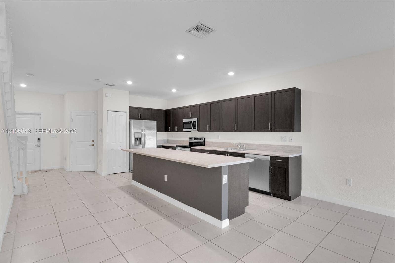 25134 SW 108th Court, Homestead, FL 33032 Kitchen featuring dark wood cabinetry, a central island with a solid surface countertop, recessed lighting, and tile flooring